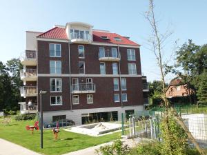 - un grand bâtiment en briques avec une aire de jeux devant dans l'établissement Ferienwohnungen Residenz Hohe Lith - Duhnen, à Cuxhaven