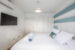 een slaapkamer met een wit bed en een flatscreen-tv bij Flower Beach Suite 1 in Playa Honda