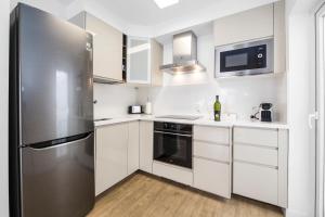een keuken met witte kasten en een roestvrijstalen koelkast bij Flower Beach Suite 1 in Playa Honda