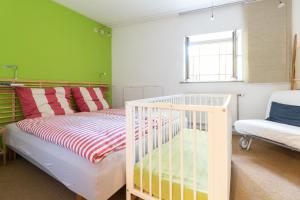 a bedroom with a crib and a green wall at Alte Falknerei in Weimar