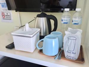 een aanrecht met kopjes, een koffiezetapparaat en flessen water bij Thai Orchid Guest House in Jomtien Beach