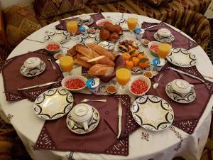 een tafel met een bord ontbijtproducten en jus d'orange bij Riad Souafine in Fès