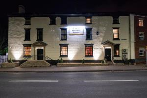 a white building with a sign on the front of it at The Kirkfield Hotel in Newton-le-Willows