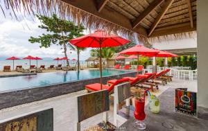 een zwembad met rode parasols en tafels en stoelen bij la plage resort & beach club in Baan Tai