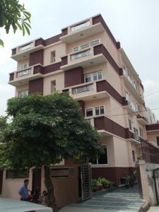 un edificio alto con un árbol delante de él en Ahuja Residency Noida, en Noida