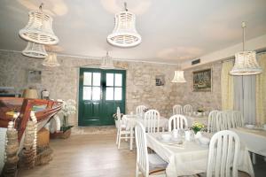 a dining room with white tables and chairs and chandeliers at Villa Rustica Dalmatia in Seget Vranjica