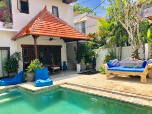 a pool in front of a house with a bench and an umbrella at Dream Villa Carissa Seminyak Centre in Seminyak