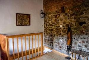 Habitación con pared de piedra y escalera de madera. en EL PAJAR DE ANGELINES en Tocon De Quentar