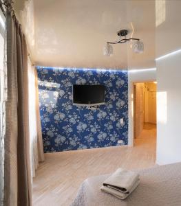 um quarto com papel de parede floral azul e uma televisão de ecrã plano em Luxury 2 Rooms Apartments in Center by Green House em Poltava