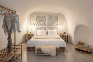 a bedroom with a white bed and two tables at Cocoon Suites in Imerovigli