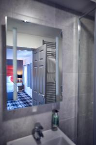 a bathroom mirror with a sink and a bedroom at The Kirkfield Hotel in Newton-le-Willows