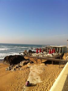 Una playa con mesas y sillas y el océano. en Apartamento da Foz, en Oporto