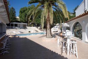 a palm tree next to a pool with tables and chairs at Abeniss Boutique B&B in Benissa