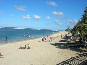een groep mensen op een strand vlakbij de oceaan bij Hôtel Le Nathania in Saint-Pierre