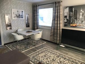 ein Wohnzimmer mit Tisch, Stühlen und Fernseher in der Unterkunft Residence 4 in Tampere