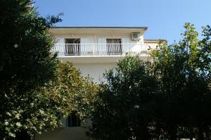 a white building with a balcony and trees at Tucepi Kamena 57 in Tučepi