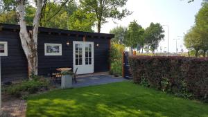 a black house with a white door and a yard at Chalet in Castricum
