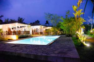 a swimming pool in front of a house at night at Odailem Resort - Talpe in Galle