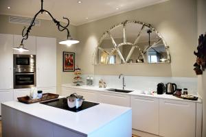 a kitchen with white cabinets and a large mirror at La Croce d'Oro Santa Croce Suite Apartments in Florence