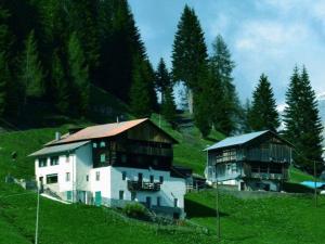 zwei große Gebäude auf einem grasbewachsenen Hügel mit Bäumen in der Unterkunft Appartamento Col di Lana Dolomites in Livinallongo del Col di Lana