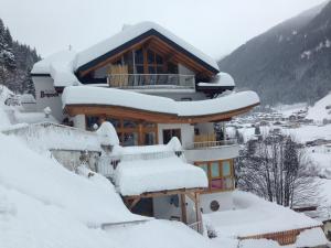 a house covered in snow on a mountain at Hotel Garni Bergwelt in See