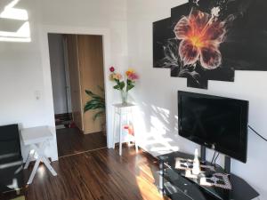 een woonkamer met een televisie en een vaas met bloemen bij Apartment Juna in Auerbach