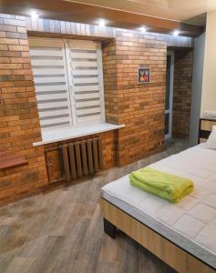 a room with a bed and a brick wall and a window at Luxury Loft в центре Полтавы in Poltava