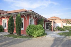 a red house with trees in front of it at The Originals Boutique, Hôtel Le Pillebois, Bourg-en-Bresse Nord in Malafretaz