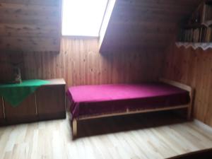 um quarto com uma cama rosa num quarto de madeira em Alyvos em Ignalina