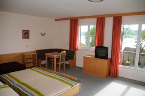 a bedroom with a bed and a desk and a television at Strandhotel in Weyregg