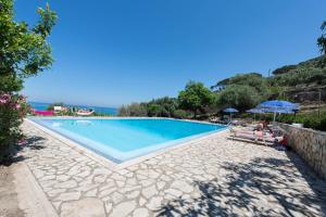 een stel op een bankje naast een zwembad bij Villa Palamara 1868 Apartments in Cefalù