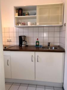 una cocina con armarios blancos y fregadero en Bed & Kitchen, en Giessen