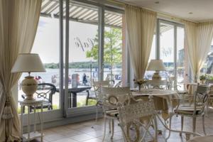 ein Esszimmer mit einem Tisch und Stühlen sowie einem großen Fenster in der Unterkunft Hotel Am Yachthafen in Waren (Müritz)