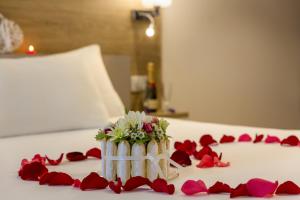 eine Vase mit Blumen auf einem Bett mit roten Rosenblättern in der Unterkunft The Originals City, Hôtel Armony, Dijon Sud (Inter-Hotel) in Chenôve