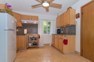 a kitchen with wooden cabinets and a ceiling fan at Mango Retreat in Kailua-Kona