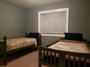 a bedroom with two beds and a window with a blind at JOFER Seattle/Renton Home in Renton