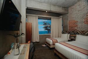 a bedroom with two beds and a window with the ocean at The Bricks Hotel in Dumaguete