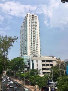 a tall white building with cars on a city street at Cozy and Bright - Trillium Downtown Surabaya in Surabaya