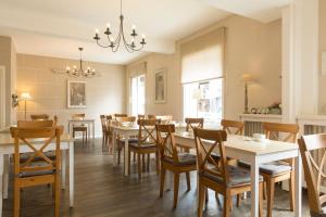 uma sala de jantar com mesas e cadeiras e um lustre em Brit Hôtel Confort Cléria Lorient Centre em Lorient