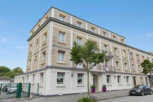 un grand bâtiment blanc avec un arbre en face dans l'établissement Brit Hôtel Confort Cléria Lorient Centre, à Lorient