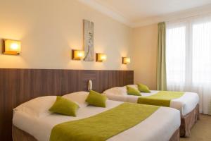 um quarto de hotel com duas camas com almofadas verdes em Brit Hôtel Confort Cléria Lorient Centre em Lorient