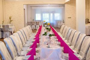 een lange tafel met witte stoelen en roze tafellopers bij Resort Jura in Kroczyce
