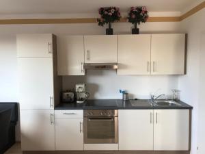 a kitchen with white cabinets and a sink at KMHeim, Cozy 103m2 apartment, with 3 bedroom and covered free parking place, close to city center in Graz