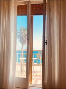 an open door with a view of a palm tree at Intero appartamento " Sea Breeze" CIS Regione Puglia in Mola di Bari