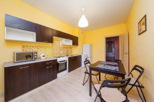 クラスノダールにあるPanorama apartments 28の黄色の壁のキッチン(テーブル、椅子付)