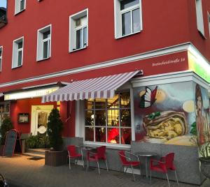 een restaurant met tafels en stoelen voor een rood gebouw bij Apartment Juna in Auerbach