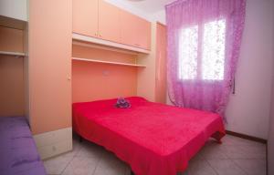 a bedroom with a red bed and a window at Ivana in Bibione
