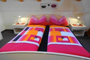 サースフェーにあるAkropolisのベッドルーム1室(赤とオレンジの枕が備わるベッド2台付)
