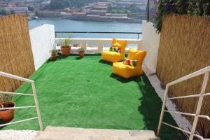 eine Terrasse mit zwei gelben Stühlen auf einem Grasfleck in der Unterkunft Oportobestview-River in Porto