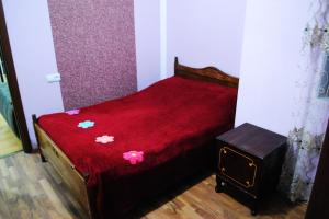 Una cama pequeña con una manta roja con flores. en Apartament GIORGI, en Borjomi